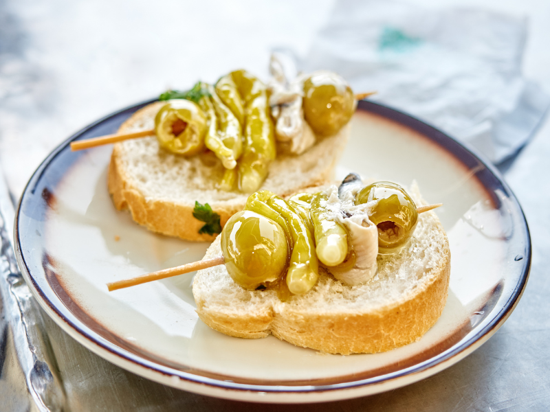 White Cantabrian Anchovies marinated witholives and peppers skewer over bread, a gilda plate