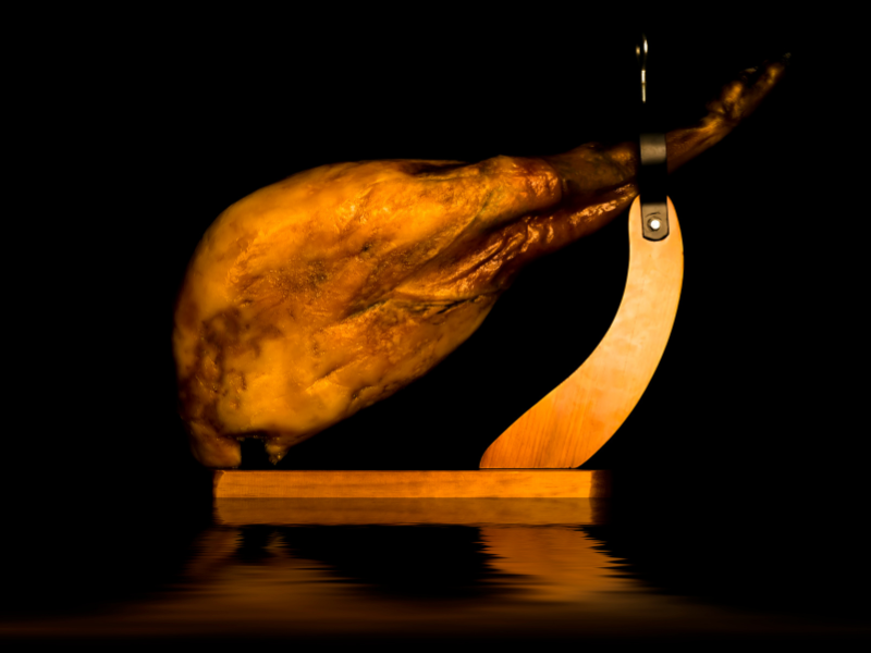 Iberico Ham "jamon de bellota" in a ham holder / ham stand on a black background. Deliberico