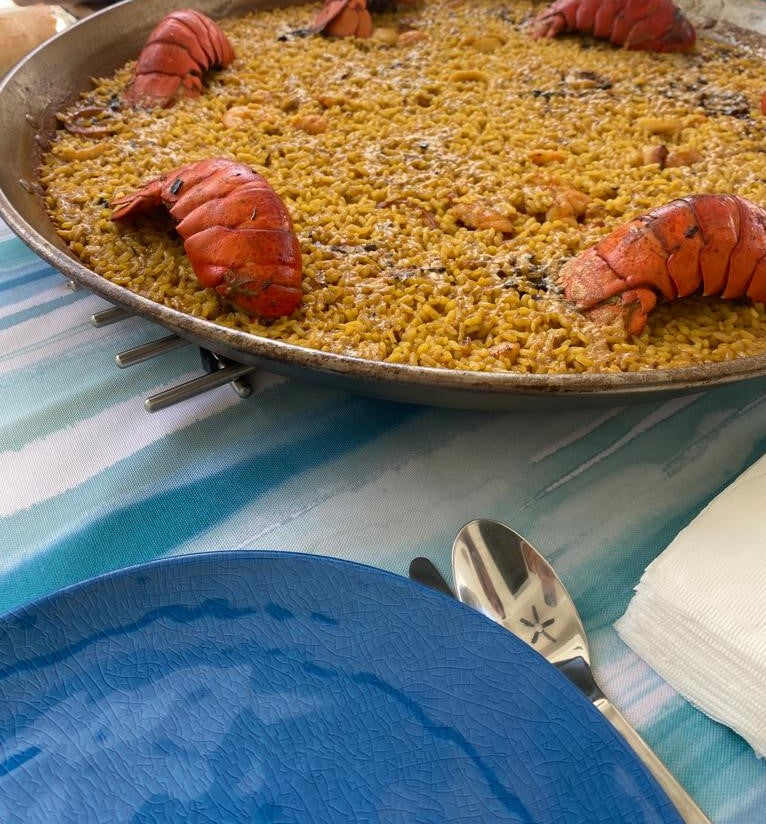Seafood paella with lobster tails and blue plate. Deliberico