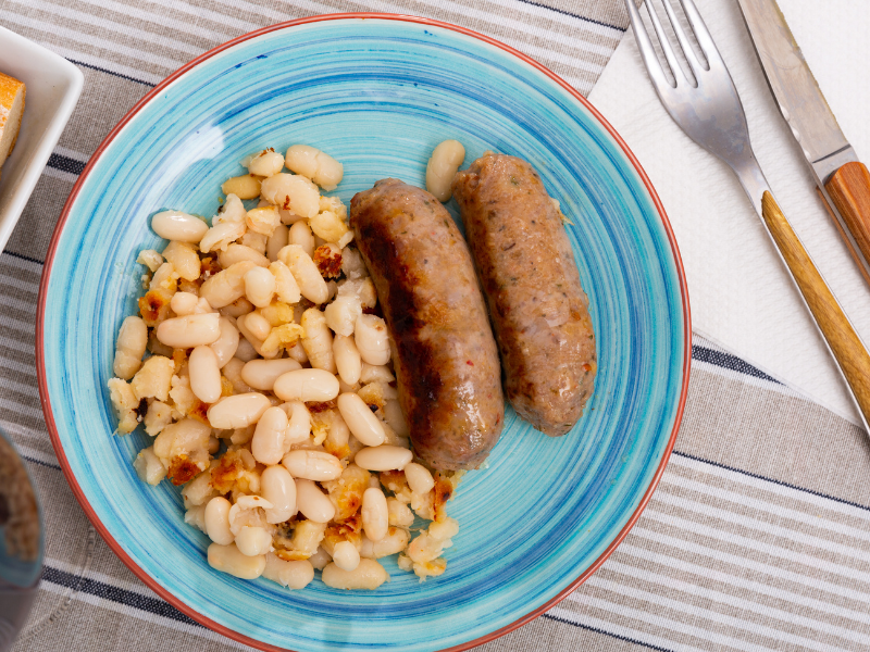 Butifarra with sauteed white beans on a blue plate
