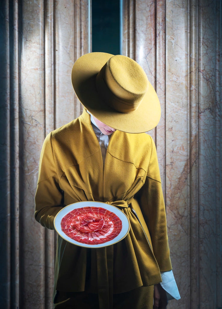 Women in yellow with a plate of Cinco Jotas iberico Ham