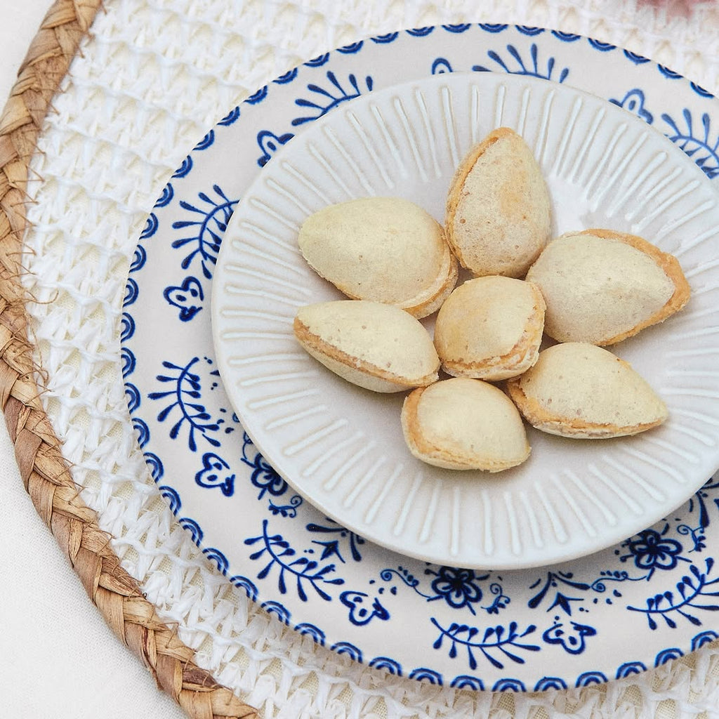 White plate with Turron filled almonds "almendritas rellenas" on a decorative blue and white plate