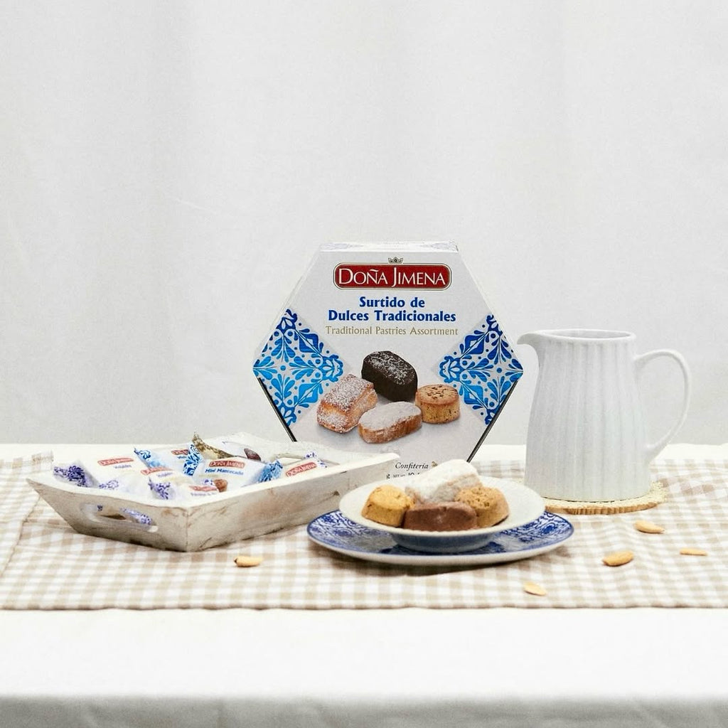 Dona Jimena assorted pastries hexagon packaging with cookies on a plate and tray on a checkered tablecloth.