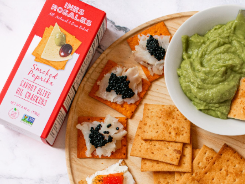 Ines Rosales Crackers Spread with guacamole, hummus, cream cheese over a wood tray