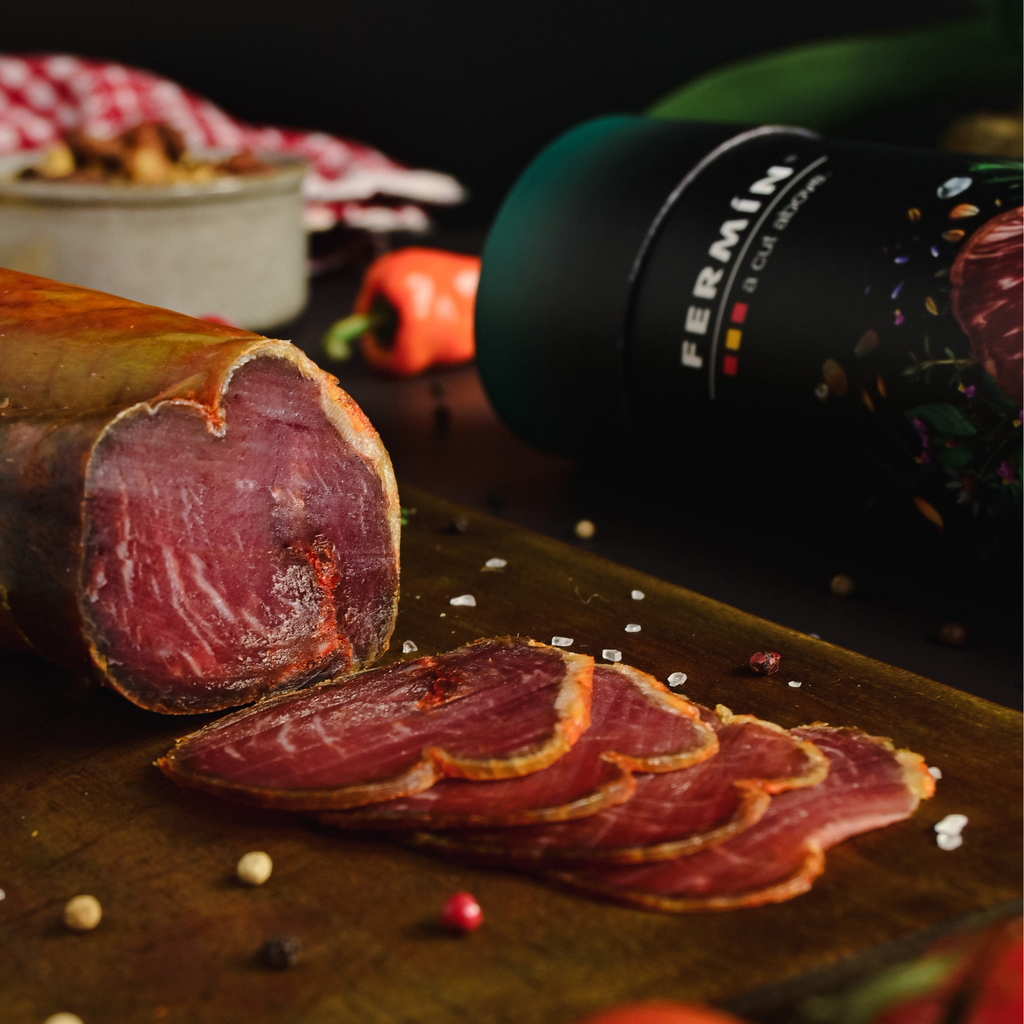 Sliced cured iberico loin on a wooden board with a tube packaging of Fermin in the background.