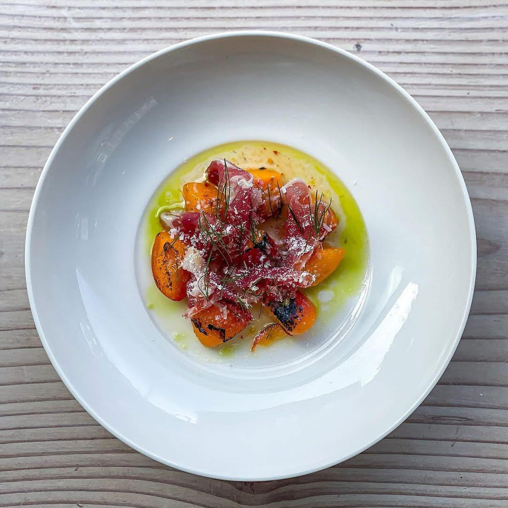 White bowl with a dish of food on a wooden surface with O-med Extra Vigin Olive Oil