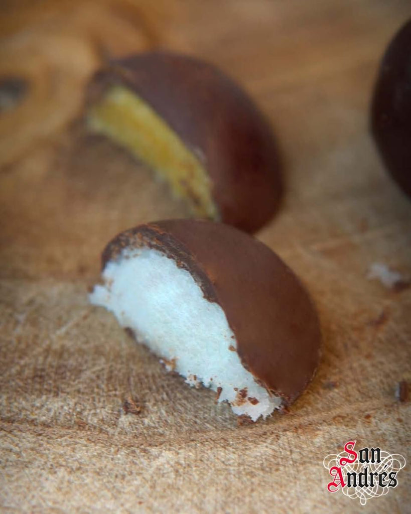Chocolate-dipped coconut and yolk  candy on a wooden surface with 'San Andres' branding.