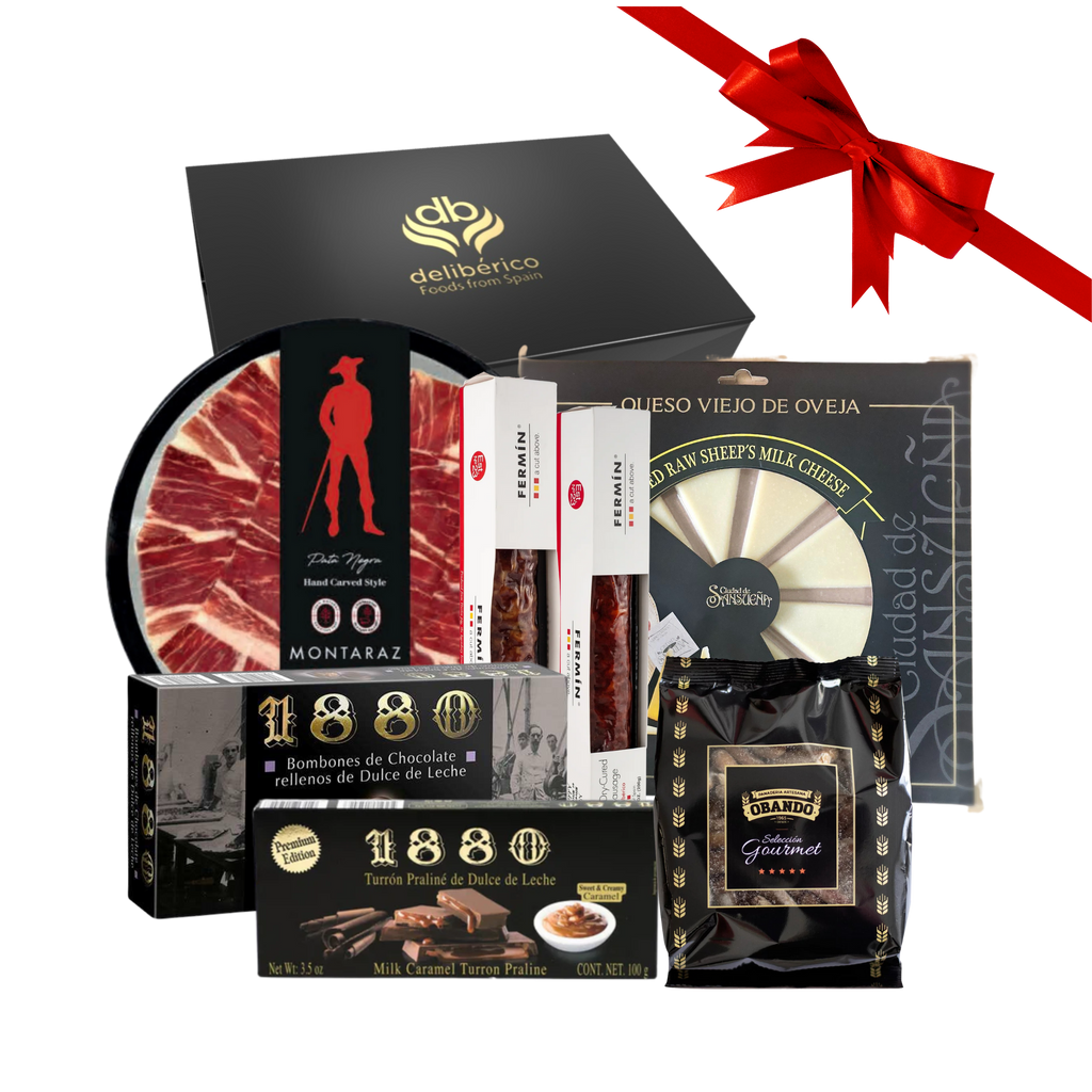 Santa Bay Gift Box from deliberico including iberico charcuterie, cheese, gourmet breadsticks and chocolate nougat and bonbons with a red ribbon on a white background.