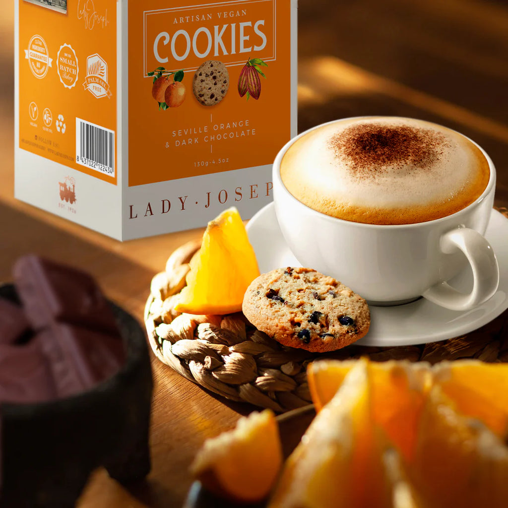 Seville Orange and 
Dark chocolate cookiwes scene with a coffee cup next to a cookie, orange and chocolate pieces and the orange product box on the side
