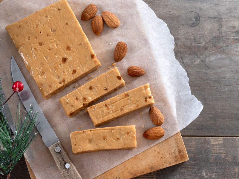 Soft Almond Nougat bar with almonds on a wooden surface
