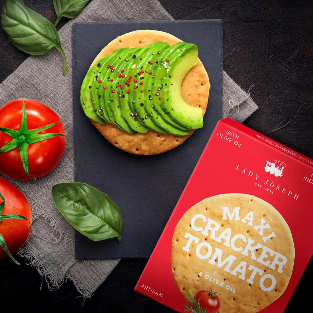 Tomato and olive oil Maxi Cracker scene with red bod a avocado oer tomato toeas on a black slate plate