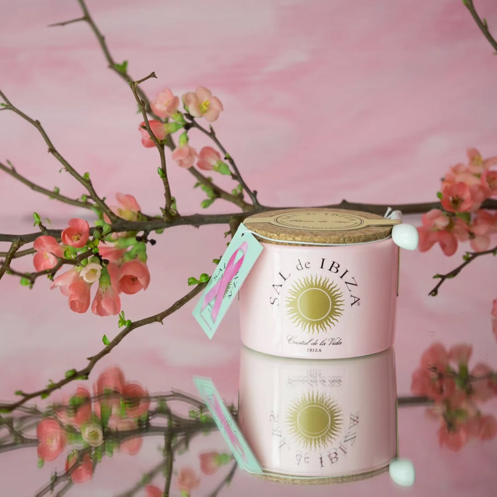  'Sal de Ibiza'Salt Pink container with cork lid and pink ribbon label on a pink  background and cherry blosson brach