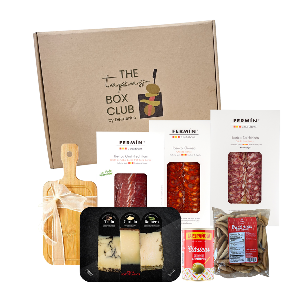 The Viva Tapas Box Club packaging with various tapas products including charcuterie, cheeses, breadsticks, olives and a wooden board on a tranparent background by the Tapas Box Club by Deliberico
