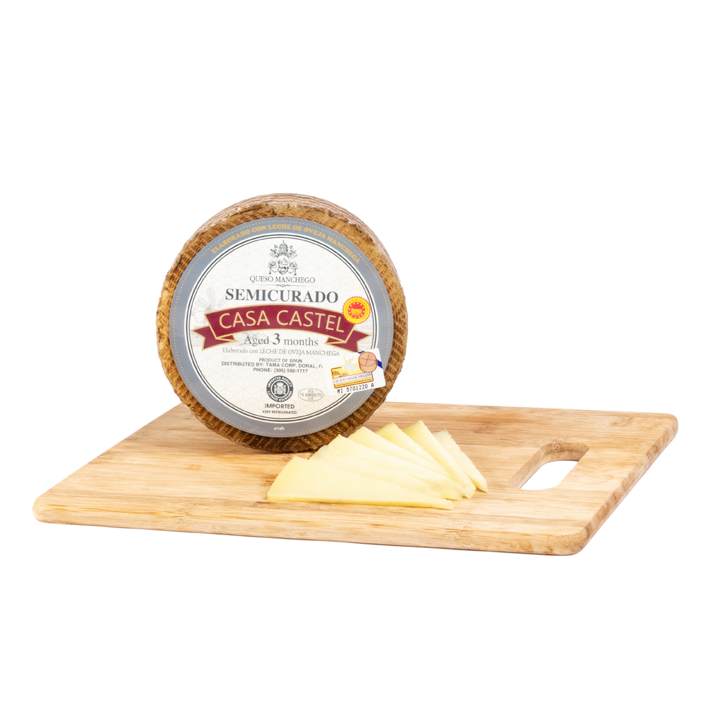 Casa Castel Manchego cheese wheel Aged 3 months and cheese slices on a wood board. Deliberico