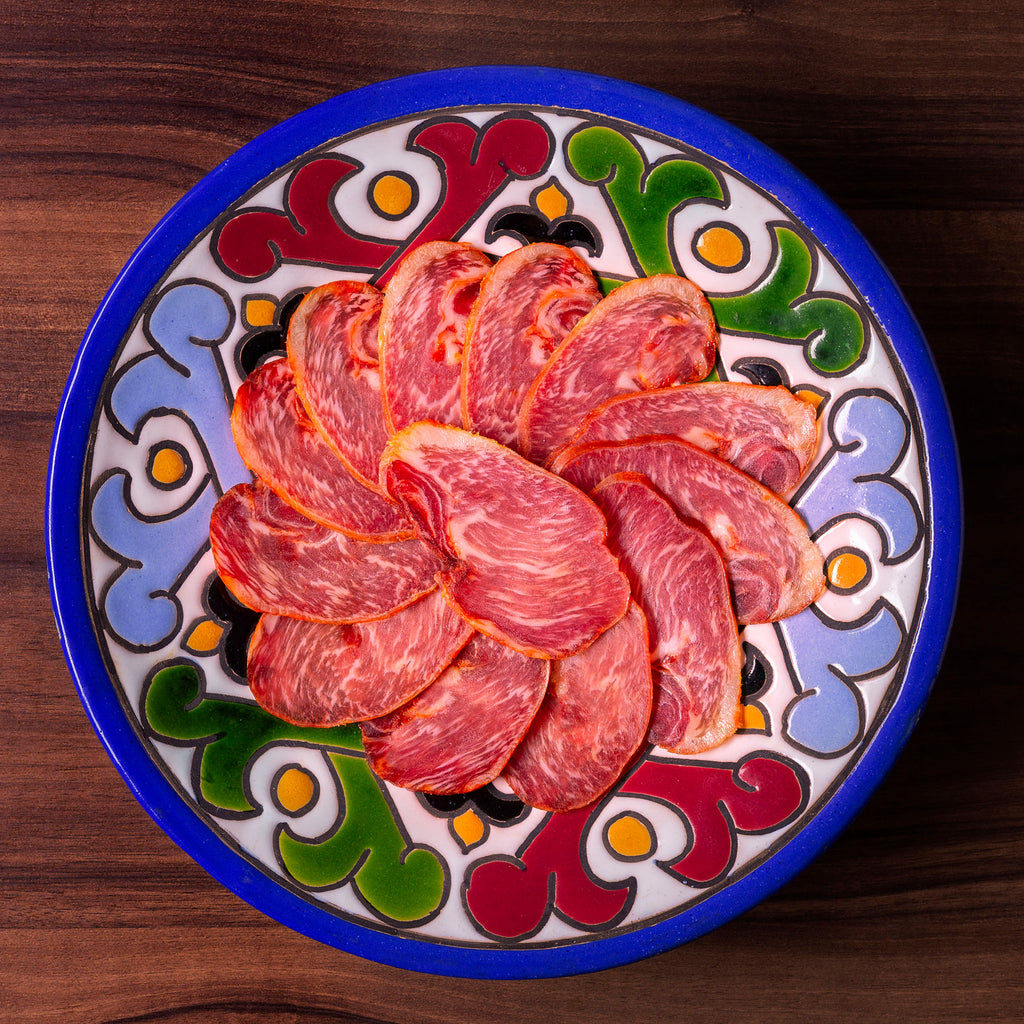 Iberico Acorn fed loin sliced on a colorful pottery plate by Fermin.Deliberico