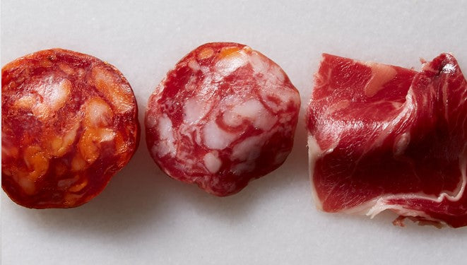 Sliced samples of all range ham, salchichon and chorizo by Marcos Salamanca on a marble background. Deliberico
