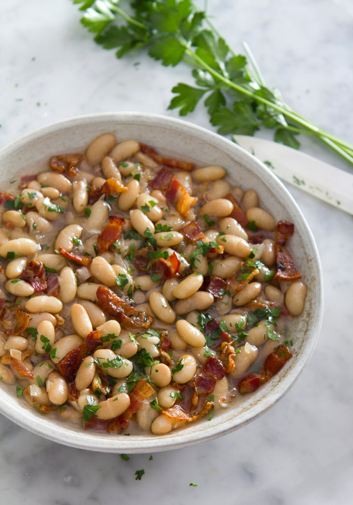 White beans with Iberico chorizo on a white bowl with parsley by Fermin. Deliberico